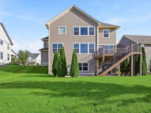 View of back of home and nicely done back yard. Very large maintenance free deck with stairs to the large patio