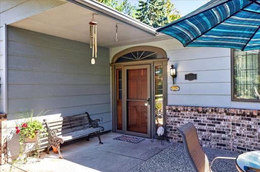 Charming covered front entrance with a decorative glass storm door and a cozy sitting area to welcome guests.