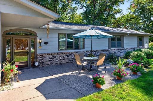 Welcoming front patio accented by colorful flowers, attractive brickwork, and beautifully maintained landscaping.