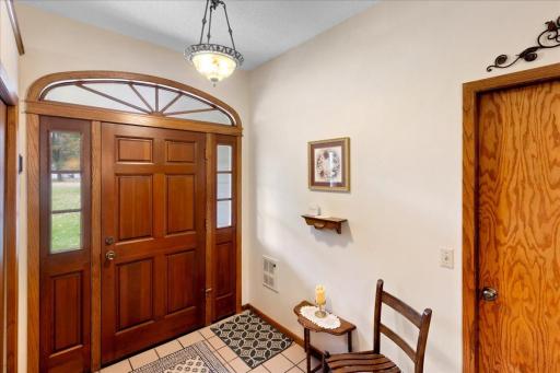 Welcoming tiled entryway featuring a beautiful wood front door with decorative glass sidelights and an arched transom window.