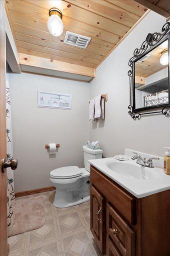 Convenient lower-level 3/4 bathroom featuring a shower, vanity with cabinet storage, and attractive wood-plank ceiling accents.