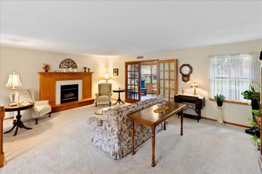 Inviting living room featuring a gas fireplace with an attractive wood mantel and French doors leading to the enclosed porch.