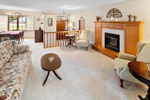 Spacious and inviting living room featuring a beautiful gas fireplace with an oak mantel, abundant natural light, and an open layout connecting to the formal dining room.
