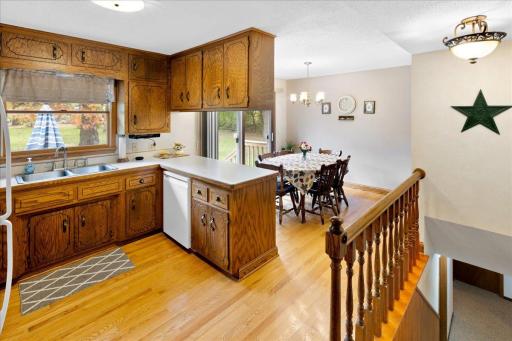 Bright kitchen and adjoining dinette featuring beautiful wood flooring, abundant cabinetry, and a sliding glass door leading to the backyard patio.