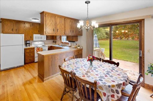 Inviting kitchen and dinette featuring beautiful wood flooring, abundant oak cabinetry, and a sliding glass door providing easy access to the backyard patio and peaceful outdoor setting.
