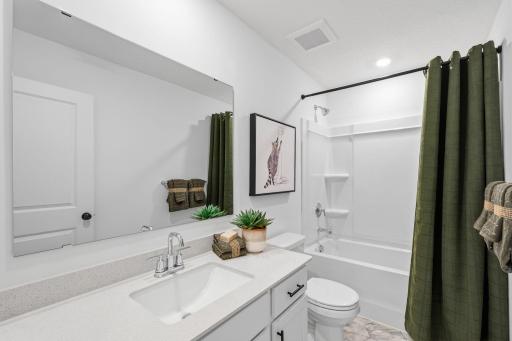 Situated near the secondary bedrooms, this full-sized bathroom comes well-equipped with a quartz-topped vanity and a combination shower and tub to maximize the interior space.