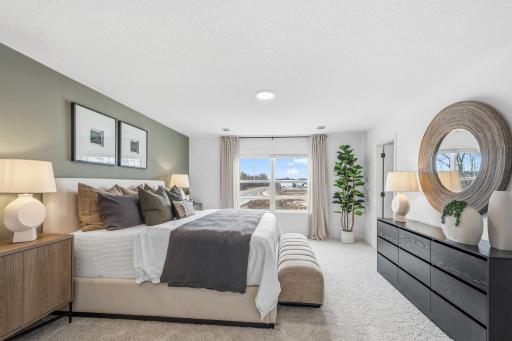 The primary bedroom embraces natural light streaming in from the large windows
