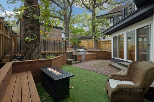 Fenced backyard, features artificial turf, brick, patio, and multiple gathering areas