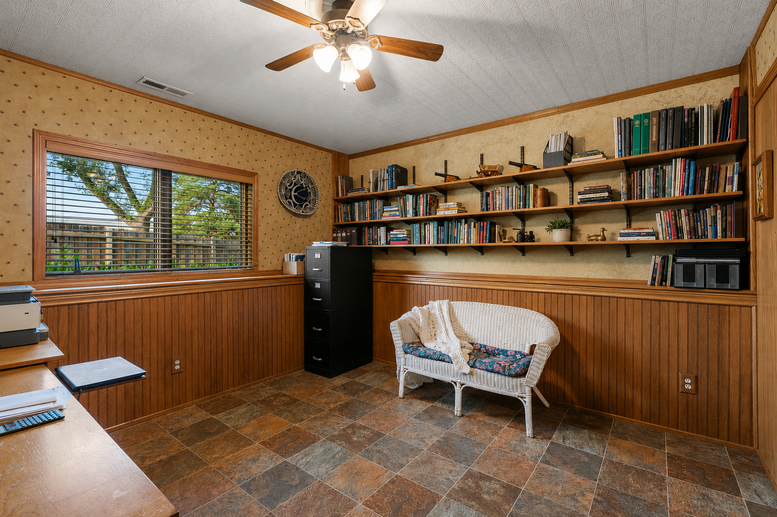 Lower-level bedroom 4, currently used as an office, is spacious with windows, custom wood paneling, built-in bookshelves, newer flooring, decorative ceiling, and a nice-sized closet