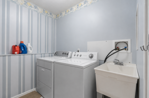 Lower-level laundry room with separate door, utility sink, and hanging area - nice sized laundry room