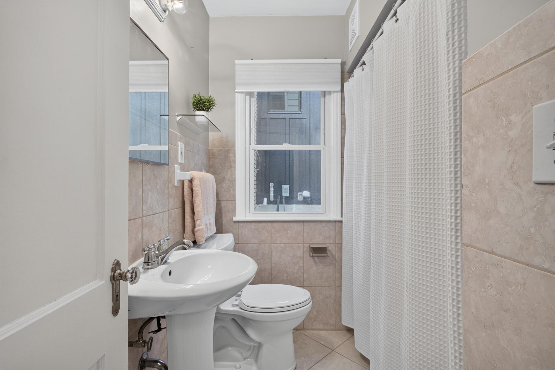 Main level full bathroom with a tiled shower