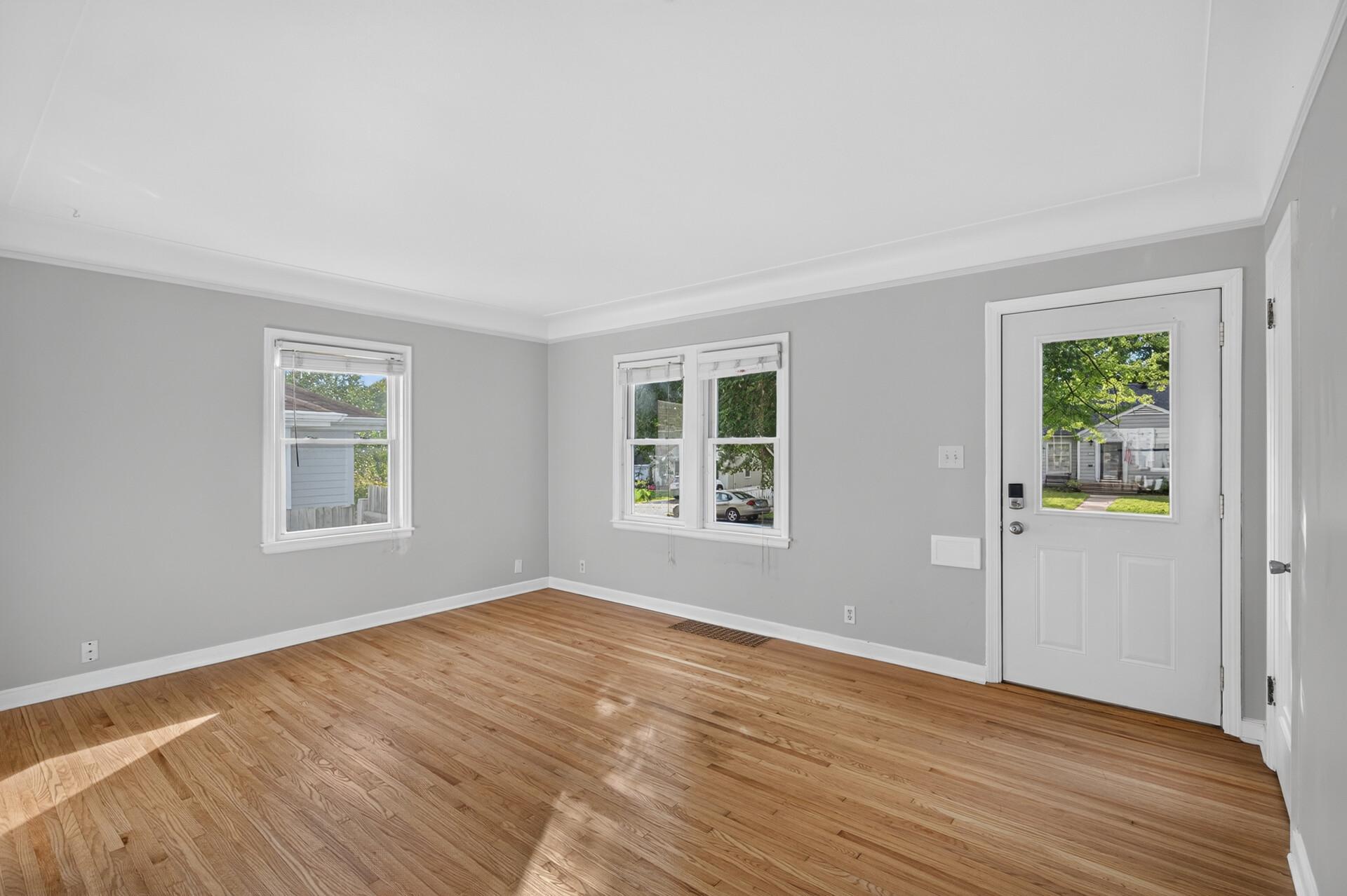 Enter into the sun-drenched living room with updated windows and original hardwood floors