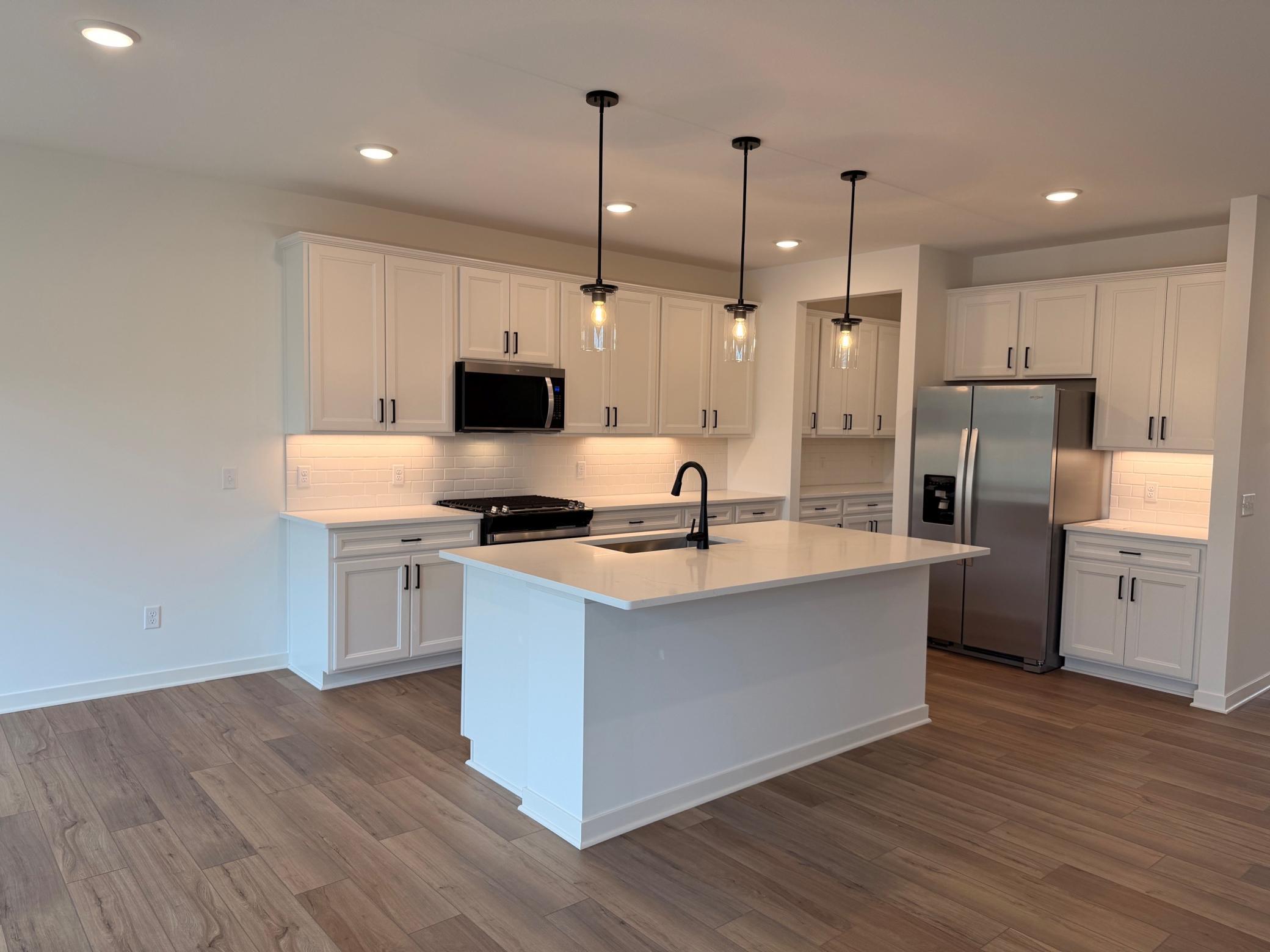 Central island offers additional prep space, seating, and storage, making it the heart of the home.