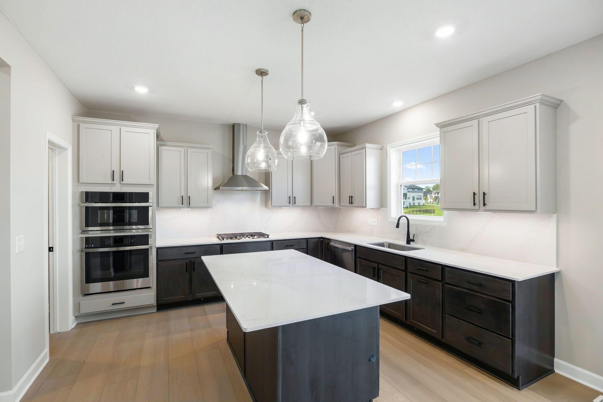 This stylish kitchen showcases a large center island, Shaker-style cabinetry, and brand-new stainless-steel appliances.
