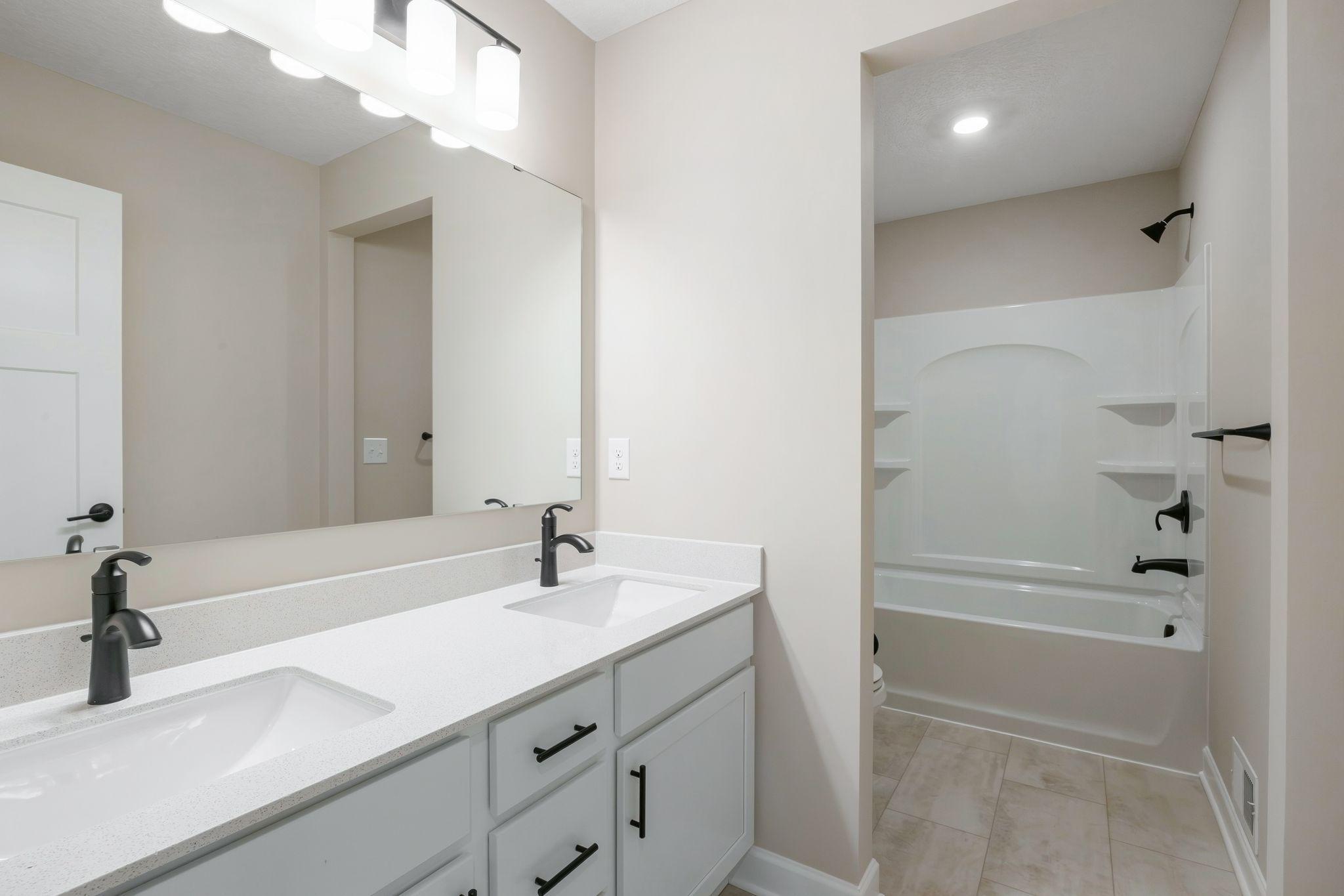 This full bathroom is conveniently located on the second floor and showcases dual sinks and a shower-tub combination.
