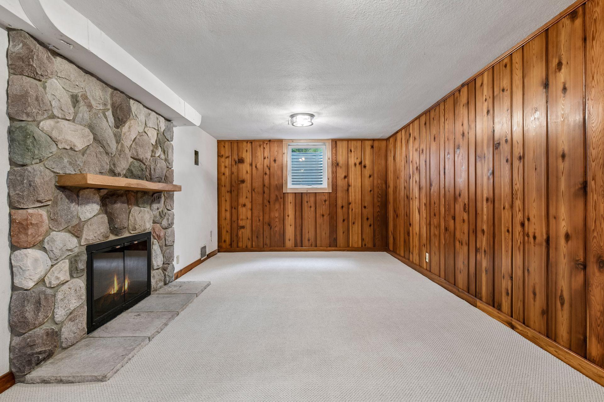Cozy lower-level family room with a striking stone fireplace and fresh new carpet. A comfortable space for movie nights, game days, or relaxing by the fire.