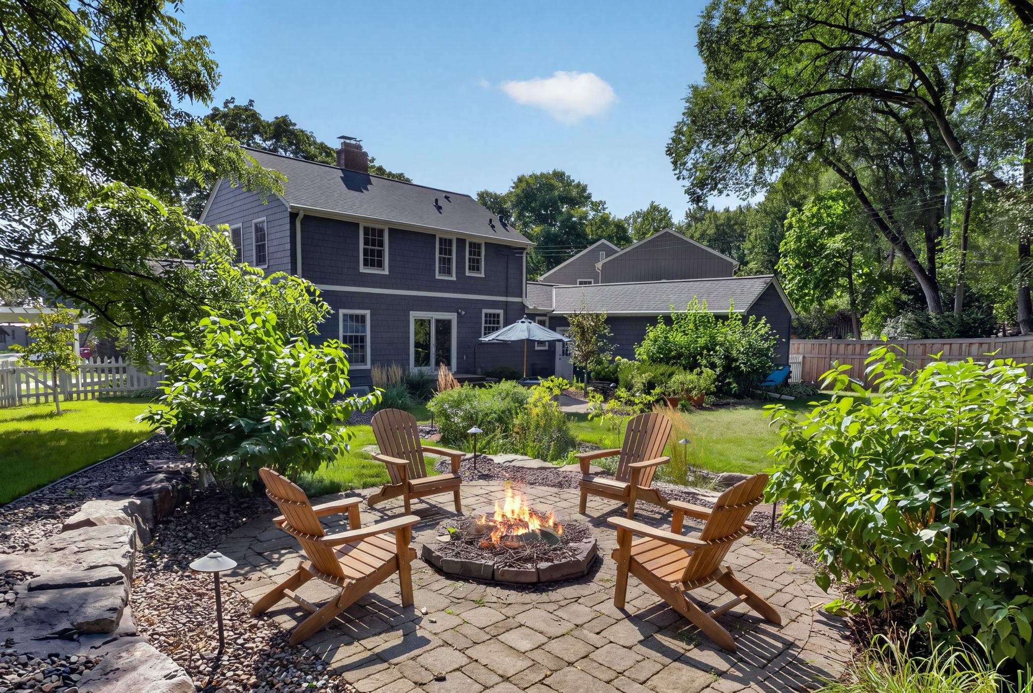 Private, sprawling, backyard with lush landscaping and an inviting fire pit patio. The perfect setting for summer evenings, entertaining, or relaxing by the fire.