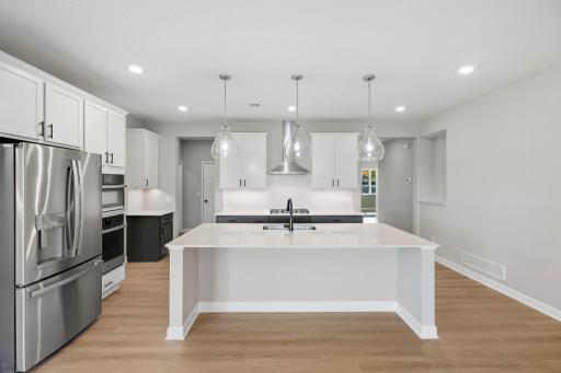 At the focal point of this modern kitchen is an inviting center island that doubles as a breakfast bar, surrounded by gleaming quartz countertops and a high-end wall oven to craft delicious meals of all sizes.