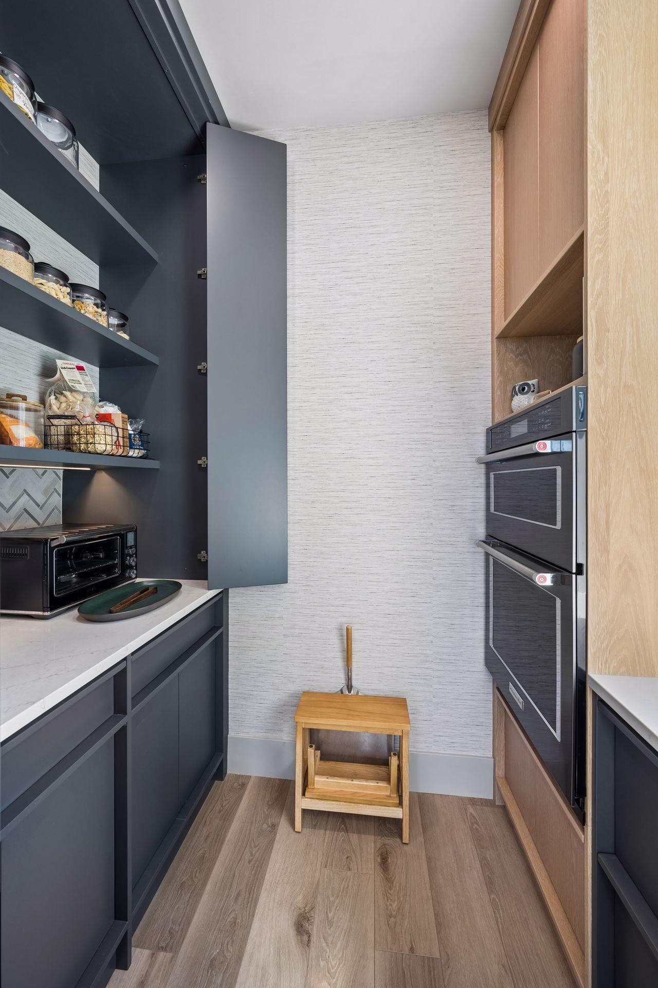 The walk-in pantry enhances the kitchen's functionality with custom cabinetry, generous storage, expansive countertop workspace, and a built-in convection oven.