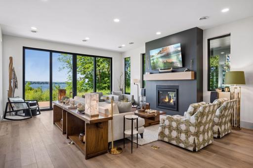 Natural light pours through expansive windows and sliding glass doors, creating a bright and inviting living space highlighted by beautiful lake views.