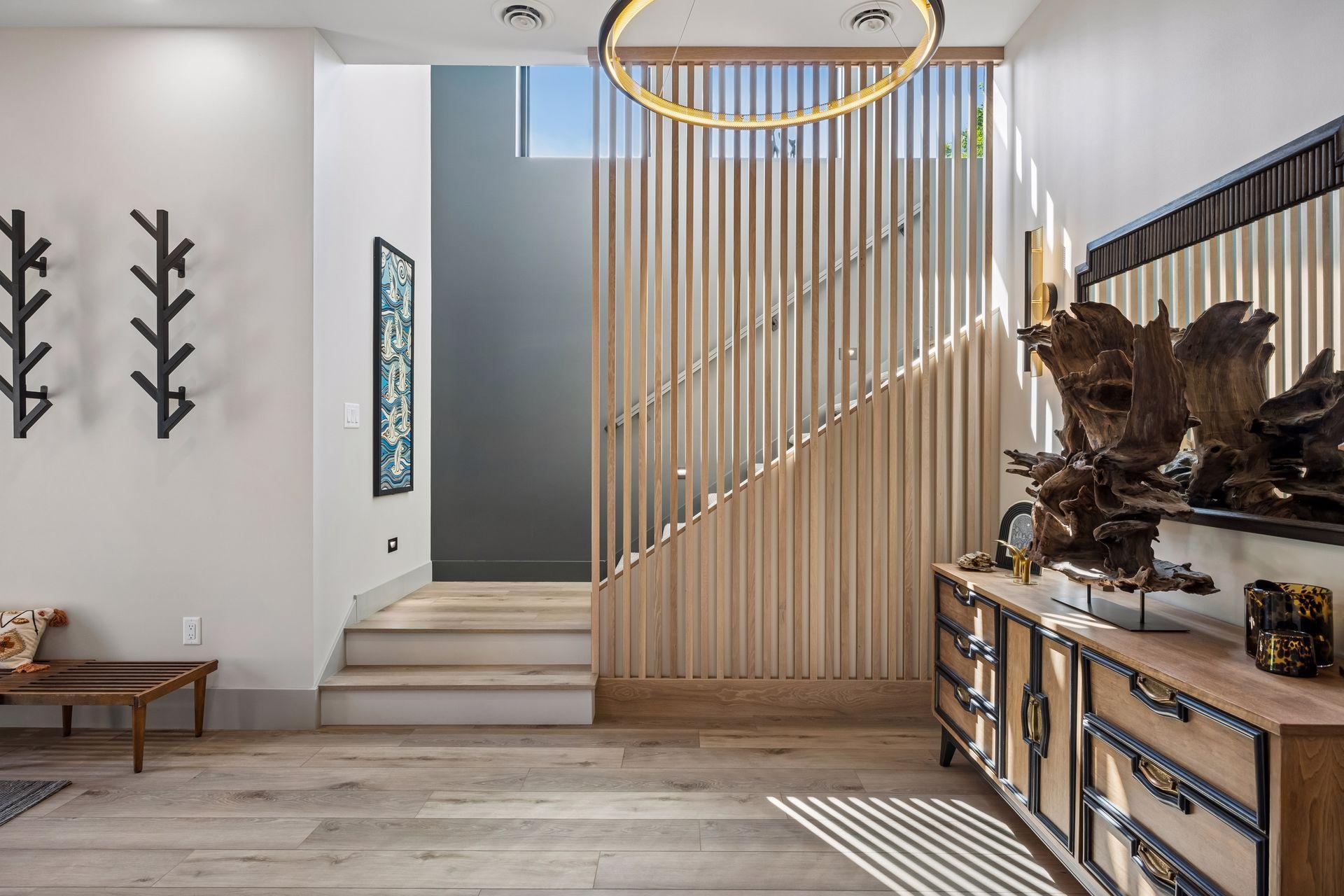 The staircase leads to the upper level and is beautifully accented by a custom wood slat feature wall, adding warmth, texture, and architectural.
