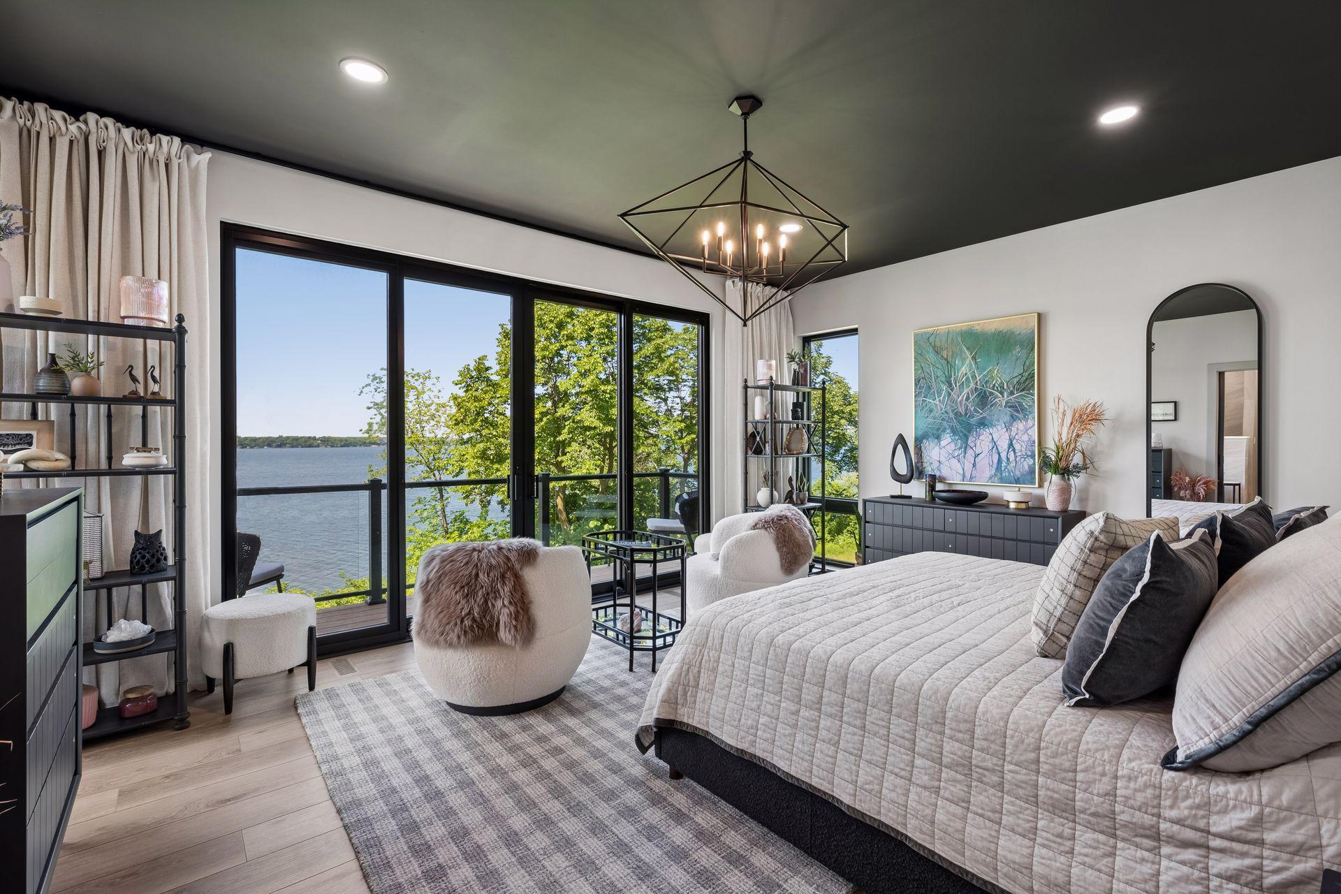 The primary suite is a private lakeside retreat, where expansive windows and sliding glass doors frame breathtaking water views and fill the room with natural light.
