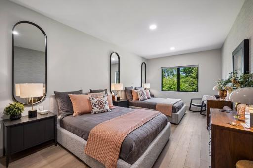 This spacious guest bedroom offers a retreat for family and friends, with ample room for 2 queen beds and a large window that bring in natural light and peaceful treetop views.
