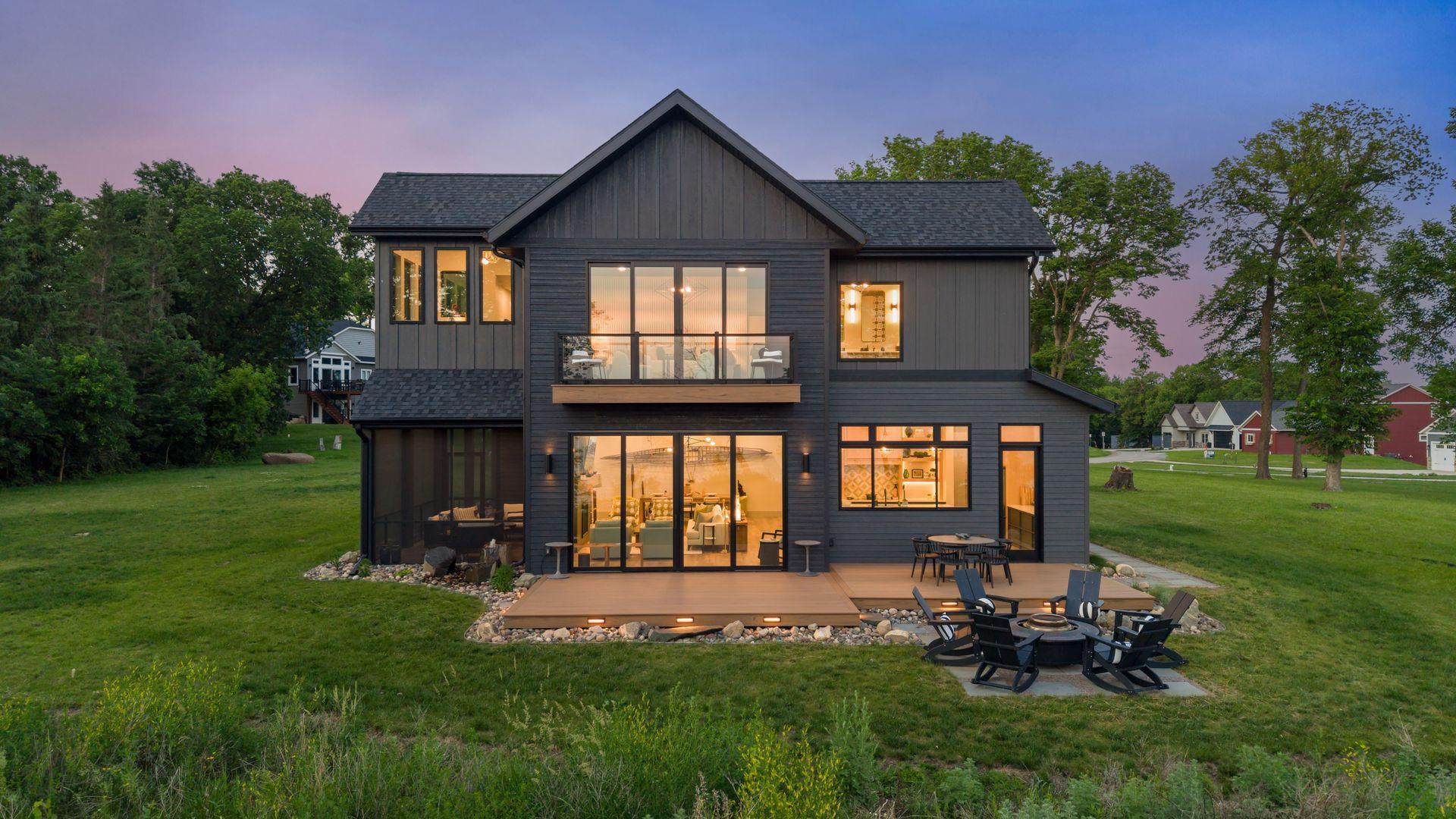 The outdoor living is impressive, with a full-width composite deck, firepit patio, grilling area, basalt water feature, professional landscaping, and layered architectural lighting.