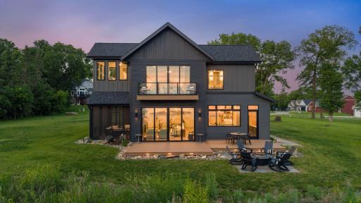The outdoor living is impressive, with a full-width composite deck, firepit patio, grilling area, basalt water feature, professional landscaping, and layered architectural lighting.