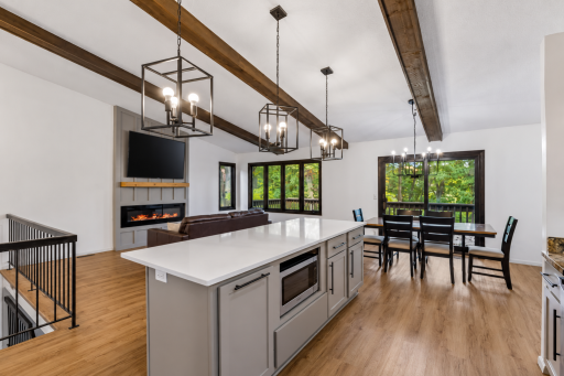 Kitchen opening up to living room and dining (TV added to image with virtual staging)
