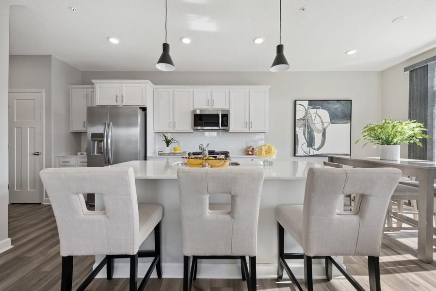 (Photo of a decorated model, actual features will vary) The spacious kitchen features a large center island, quartz countertops, recessed lighting, under mount sink, LVP floors, stainless appliances and more!