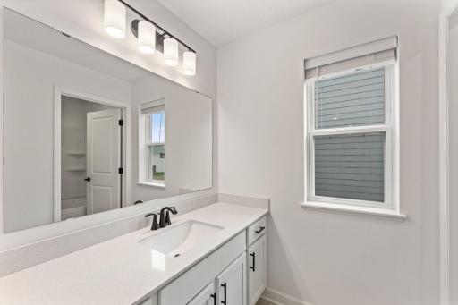 In a well-thought-out design, this full-sized bathroom features a large quartz-topped vanity that can close off from the shower-tub combo in a practical manner.
