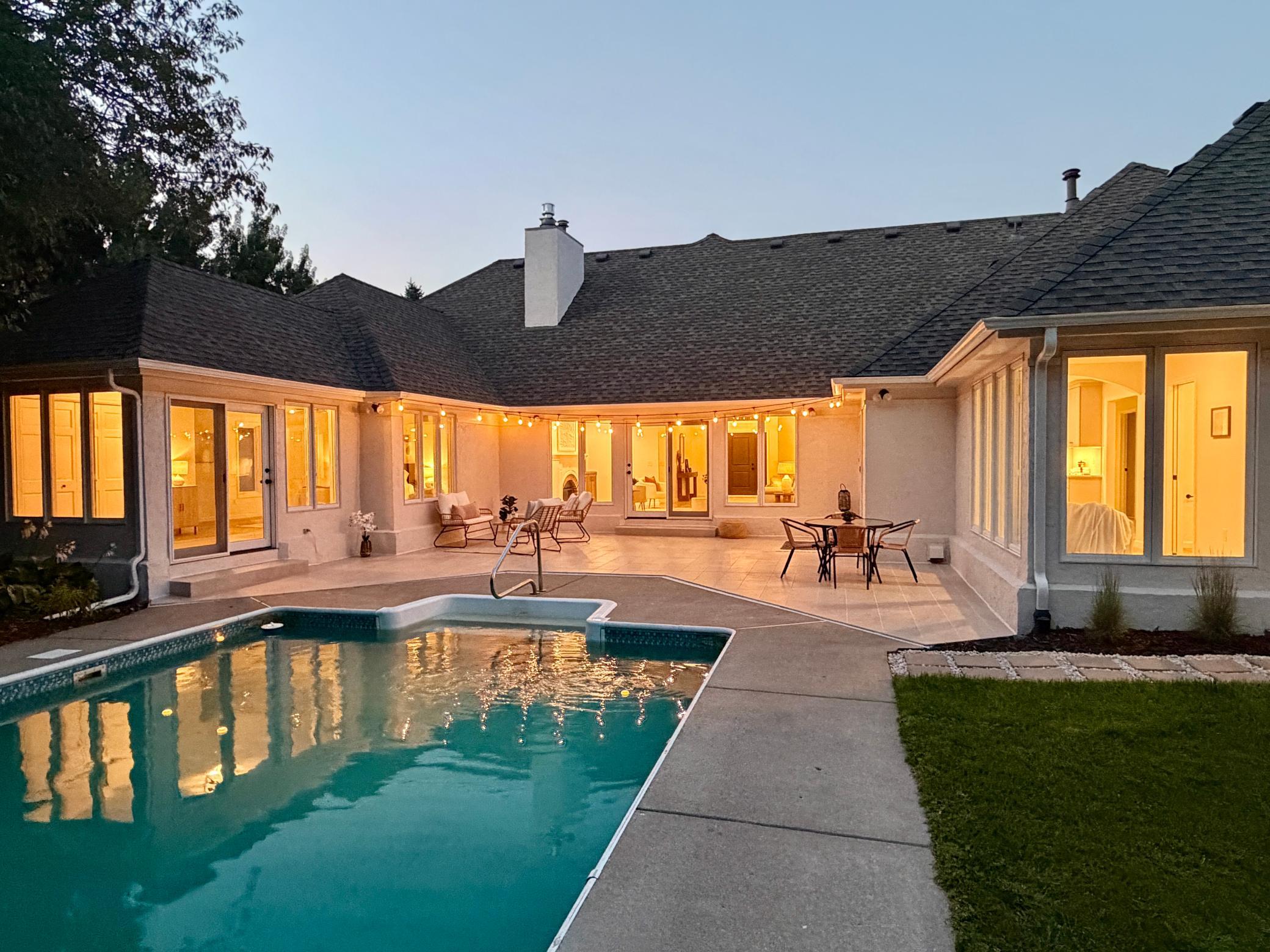 A twilight photo exemplifies how easily the patio and pool may be accessed from several rooms. Ample under-soffit lighting makes this area well into the night.