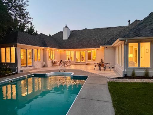 A twilight photo exemplifies how easily the patio and pool may be accessed from several rooms. Ample under-soffit lighting makes this area well into the night.
