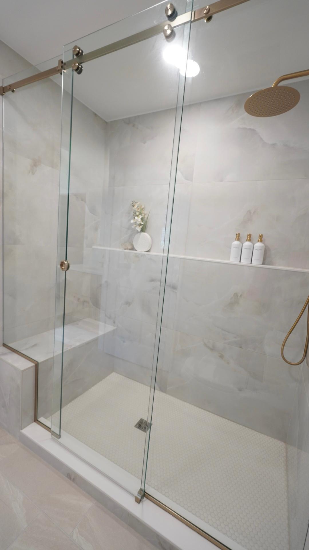 The spacious owners' shower is everything high design and functional with both a built-in bench and a wall-to-wall shelf.