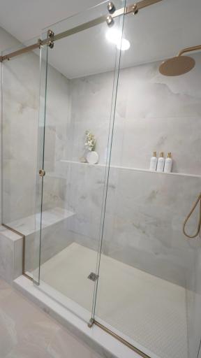 The spacious owners' shower is everything high design and functional with both a built-in bench and a wall-to-wall shelf.