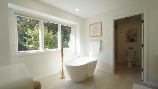 The generous main room of the primary bath is filled with natural light which highlights the spacious, freestanding tub.