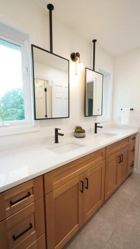 The Jack and Jill bath between bedrooms 3 and 4 provides ample counter space on the custom double vanity and ample light from windows that are enhanced by the sleek, ceiling-mount mirrors. Not pictured is a separate shower room.