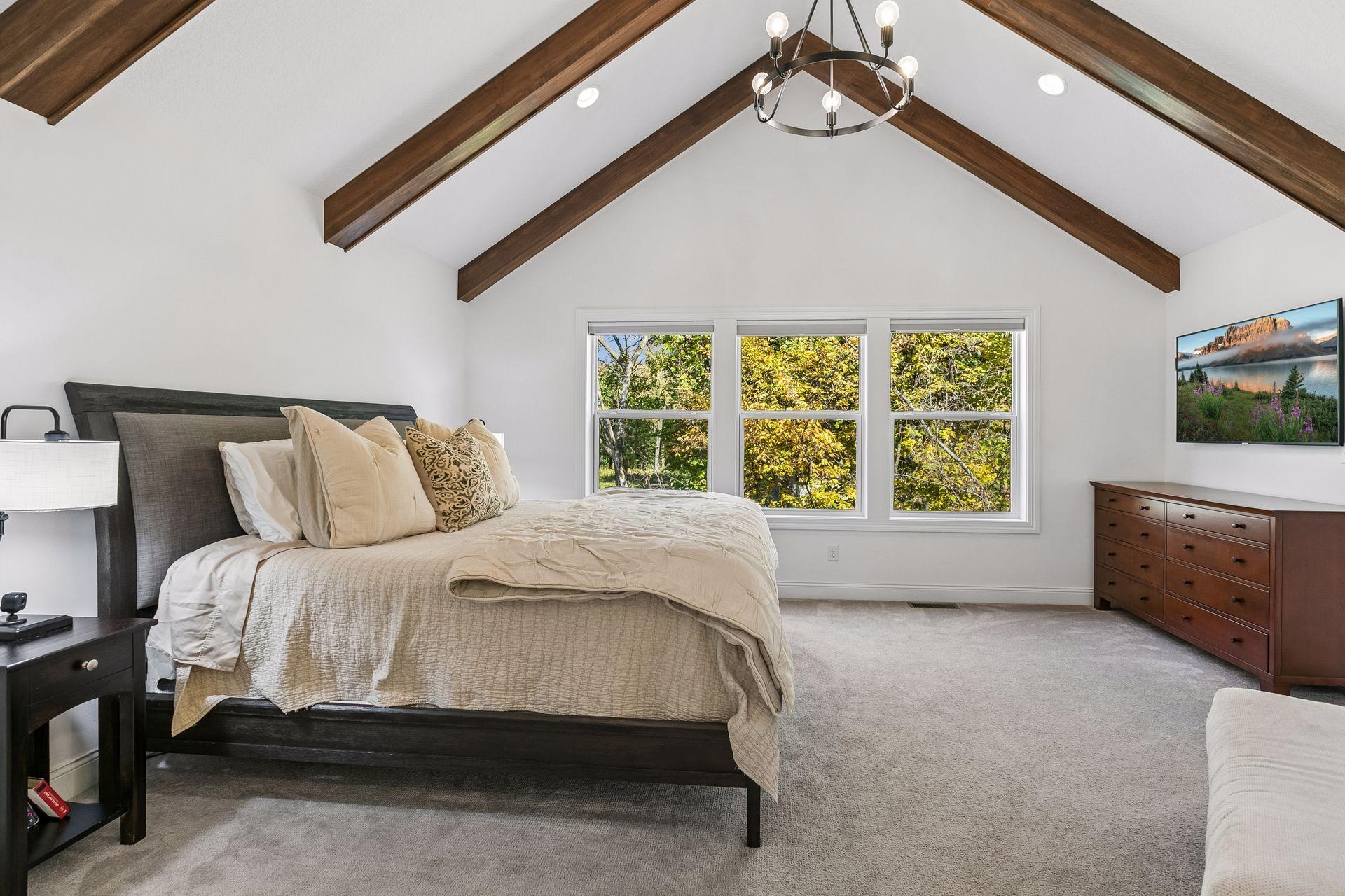 Spacious primary bedroom with vaulted ceilings and exposed beams.