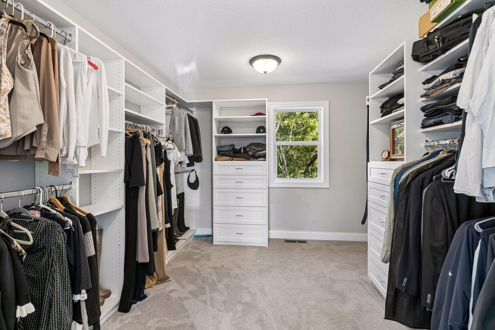 Primary walk-in closet features a Closet by Design closet system and connects the primary suite to the upper-level laundry room.