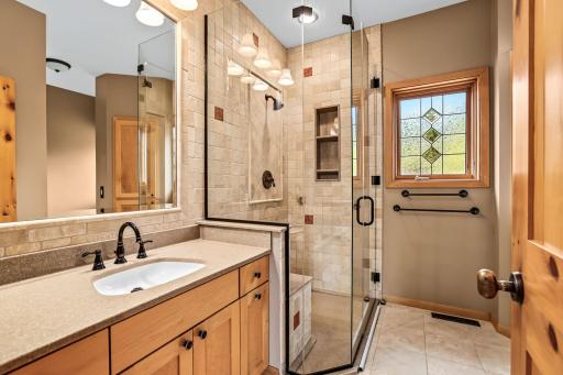 Fully renovated main floor primary bath with floor-to-ceiling custom tiled shower and jetted tub.