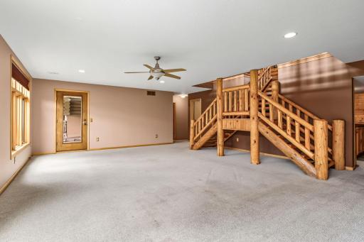 The expansive walkout lower-level family room offers a great space for entertaining. Recessed lighting, in-floor heat & oversized windows create a warm and inviting atmosphere, while the custom log staircase continues the home's Northwoods charm.