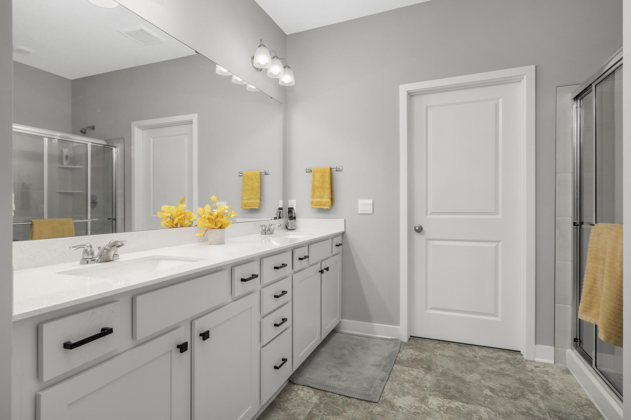 Private primary bathroom with a dual sink vanity.. The door in the photo leads to a HUGE closet. In other models, this is closed off and is a third tandem stall in the garage.
