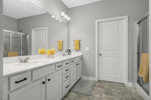 Private primary bathroom with a dual sink vanity.. The door in the photo leads to a HUGE closet. In other models, this is closed off and is a third tandem stall in the garage.