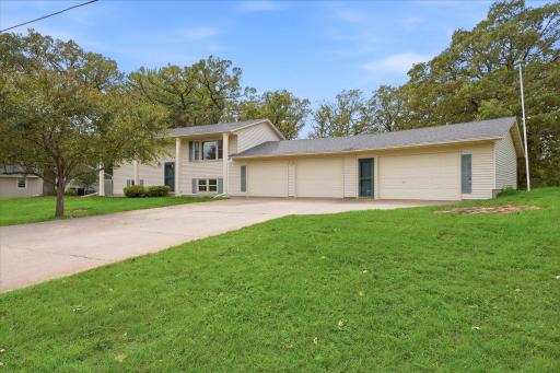Welcoming front exterior with a large four-car garage, generous driveway, mature landscaping, and plenty of additional parking space.