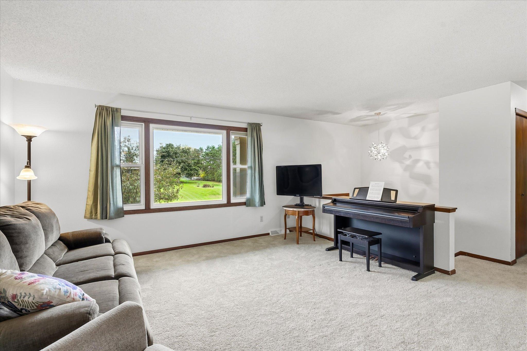 Spacious living room featuring new carpet, neutral finishes, and a large picture window bringing in plenty of natural light.