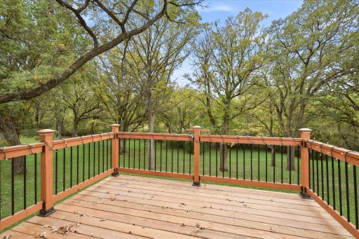 Spacious deck overlooking the beautiful, tree-filled backyard, offering plenty of room for grilling, outdoor dining, entertaining, and relaxing while enjoying the peaceful natural surroundings.