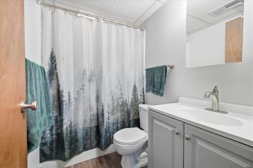 Updated lower-level full bathroom featuring a tub/shower combination, updated vanity, LVP flooring, and fresh neutral finishes for a clean, modern look.