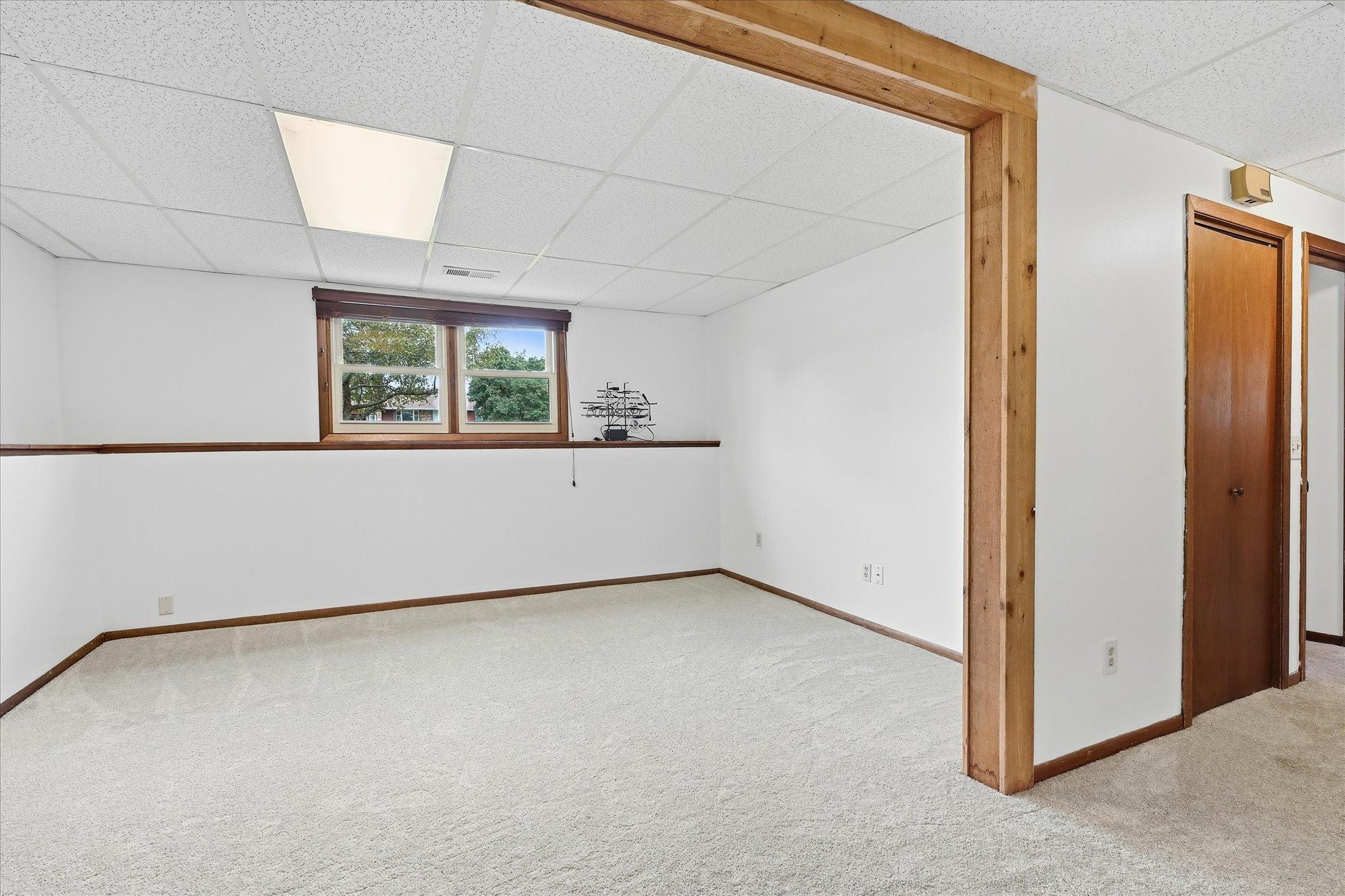 Spacious lower-level family room with neutral finishes, new carpet, and plenty of room to create a comfortable entertainment area, game space, or additional gathering area.