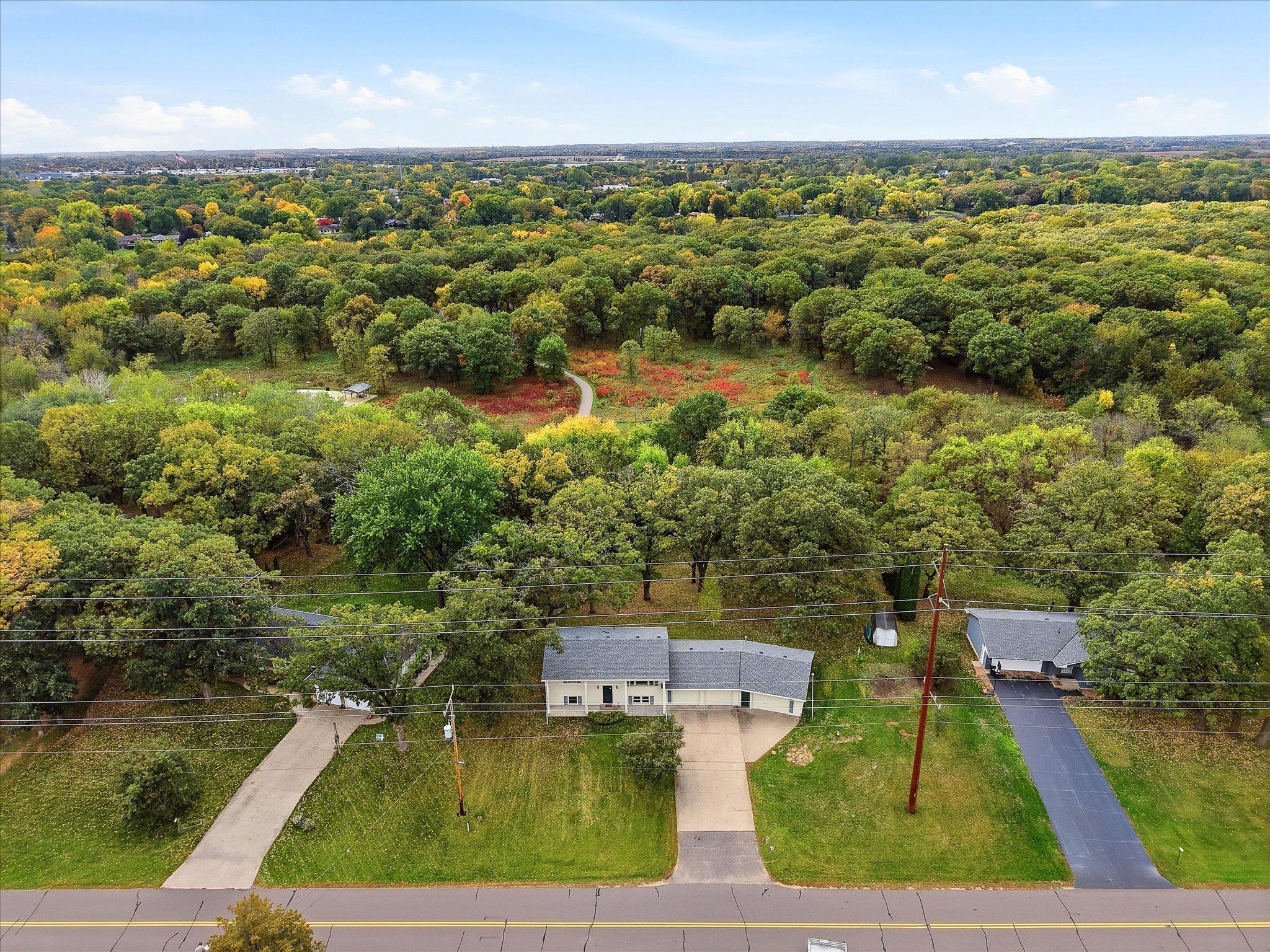 Aerial view showcases the home’s exceptional setting directly adjacent to Bridgeview Park Reserve, with acres of preserved natural beauty and the Mississippi River beyond.
